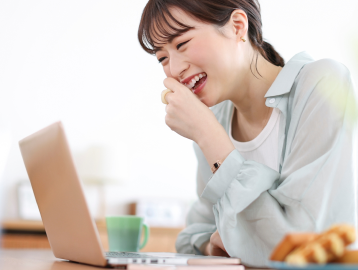 女性がPCに向かって笑っている写真
